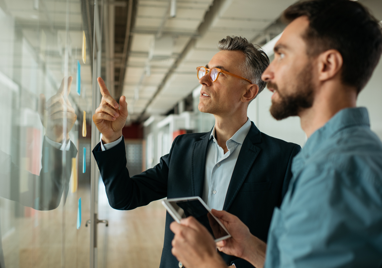 Business professionals point at chart on board.