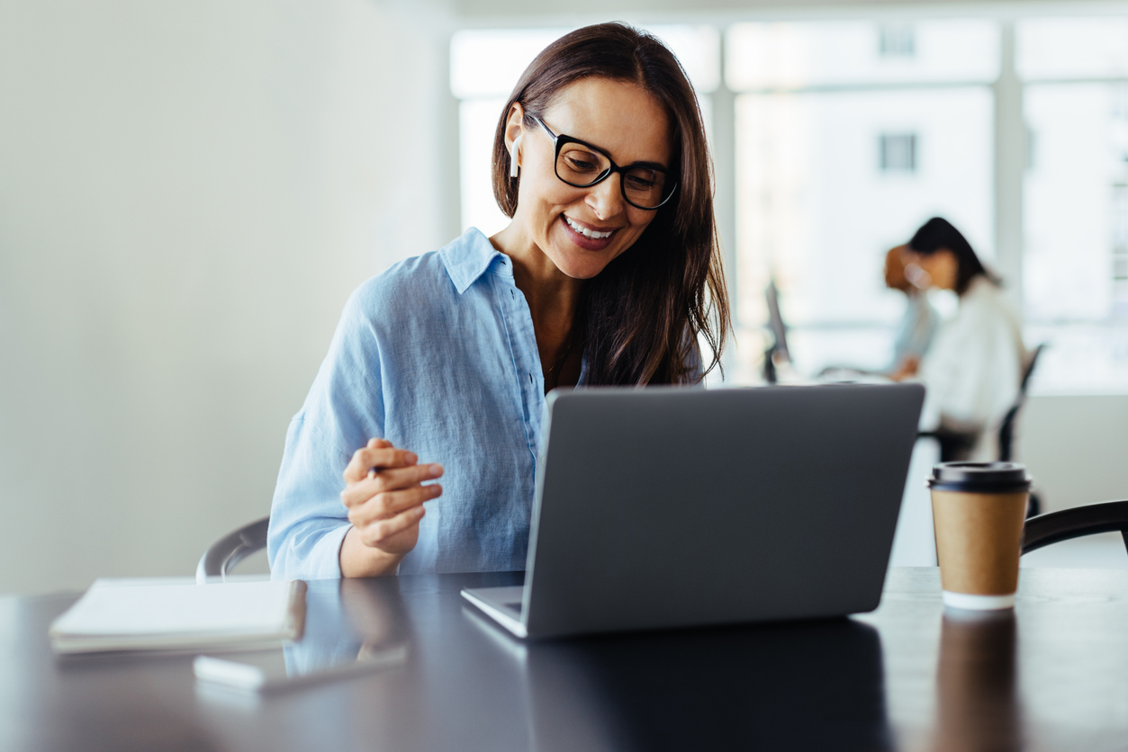 Business professional smiles at laptop.